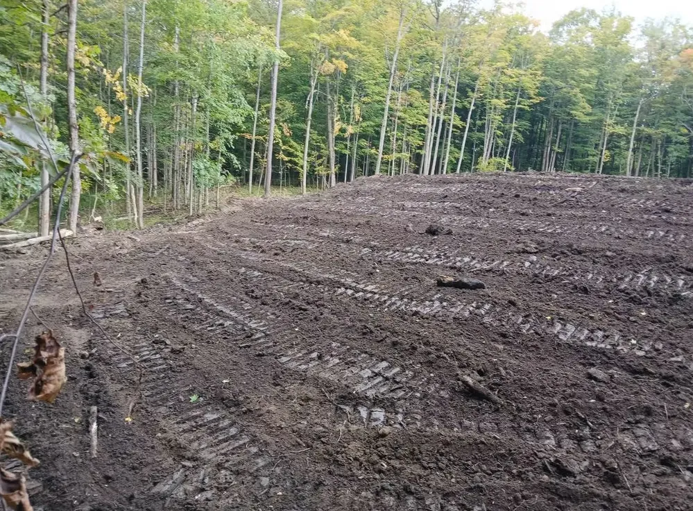 Cleared and graded building lot with tracked-machine marks after Landmark Enterprises site prep in Chautauqua County, NY